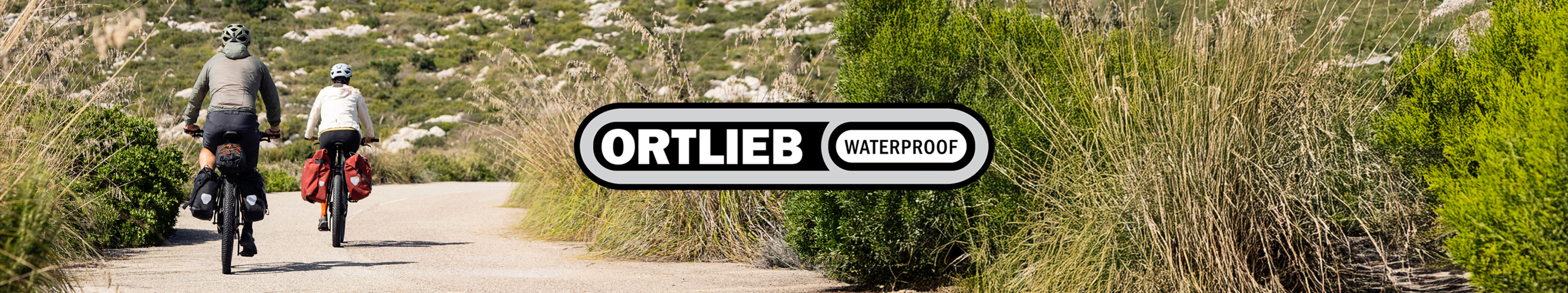 Twee sportieve mensen fietsen met Ortlieb-fietstassen door de natuur.