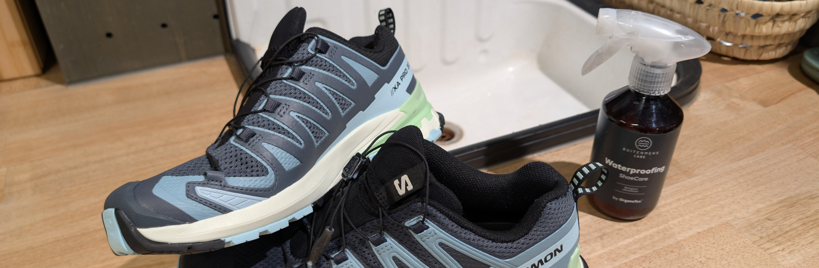 Twee Salomon-schoenen liggen naast een impregneerspray.