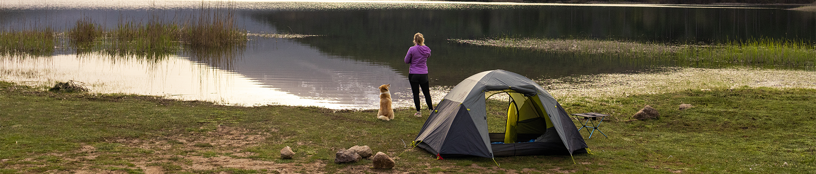 vrouw en hond bij tent kijken uit over meer