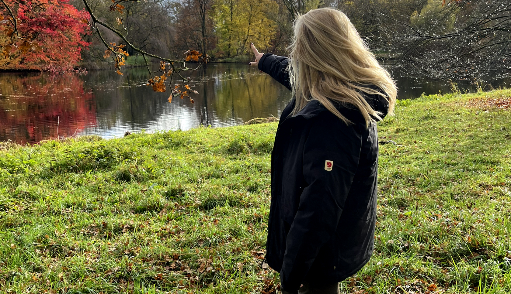 Meisje wijst naar bomen met fjallraven jas aan
